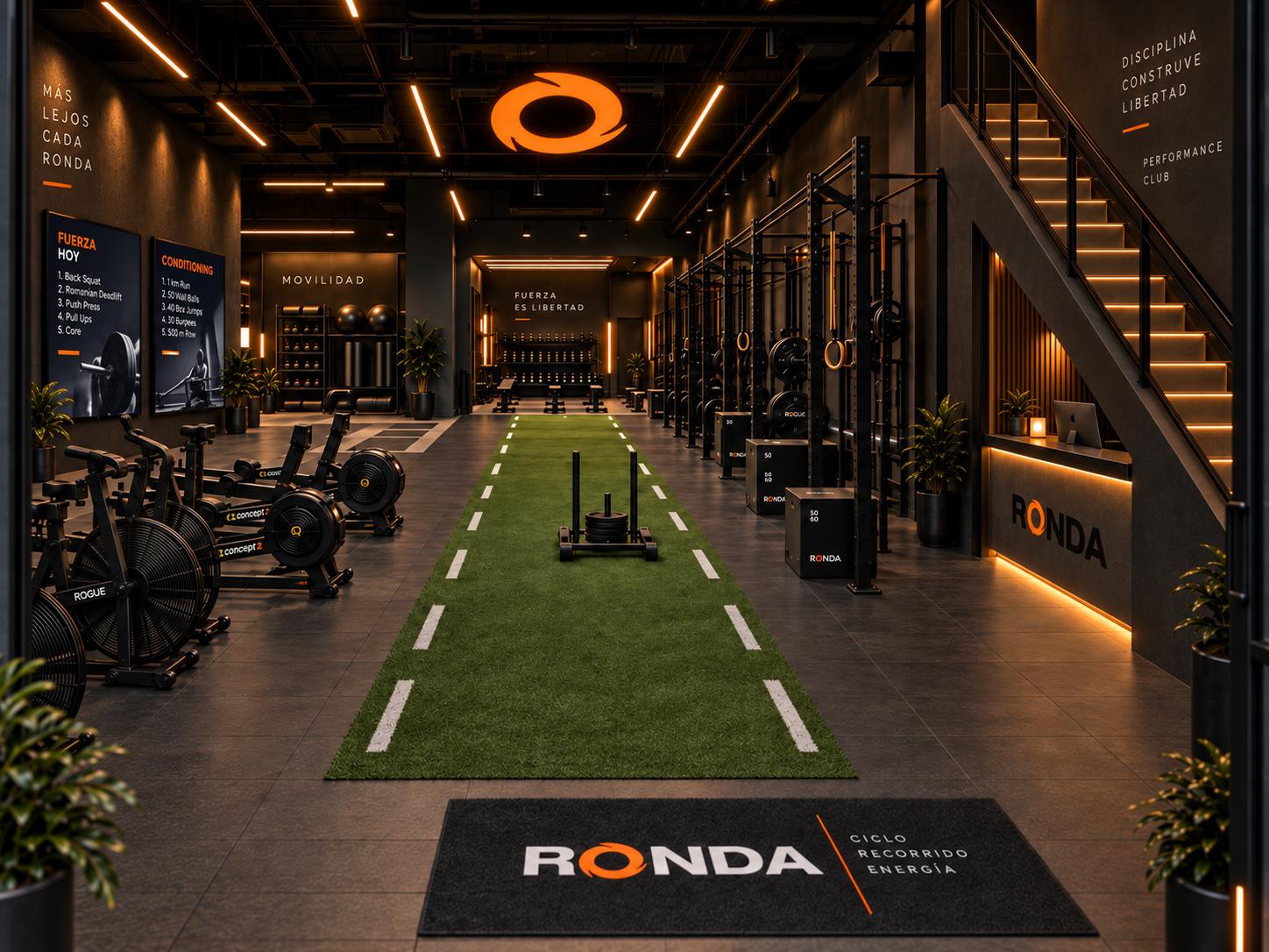 Render del futuro local de RONDA: pista de césped con trineo al centro, remos y bicis de aire a la izquierda, racks a la derecha y la O naranja iluminada en el techo